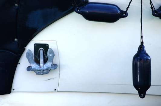 The side view of a motorboat with a ship anchor and floating buoys.