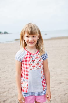 Smiling cute young girl at beach looking to side with ocean in background
