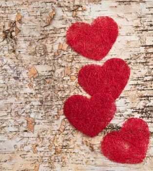 Four red hearts on birch bark background