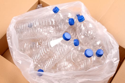 Rubbish bag with bottles of water for recycling inside a cardboard box .