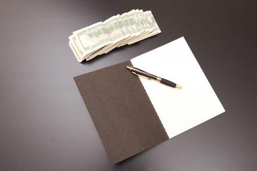 Lots of dollars with an open copybook.
