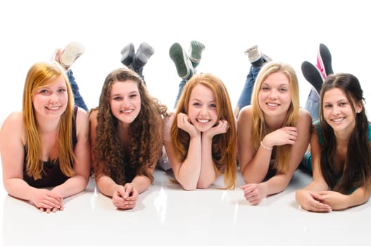 Five young teenager girl lying on a white floor laughing and looking at the camera.