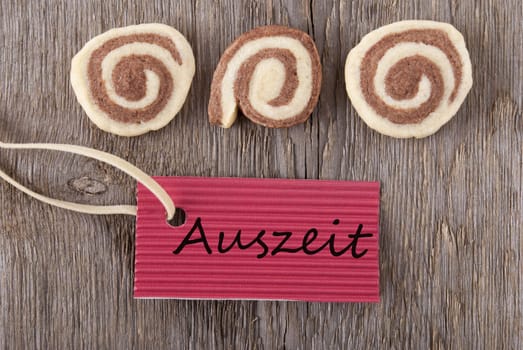 a red label with the german word Auszeit which means downtime and some cookies on a wooden background