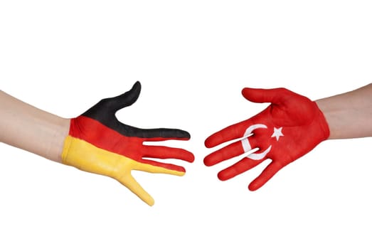 two hands, one painted with the german flag colors, the other one with the turkey flag