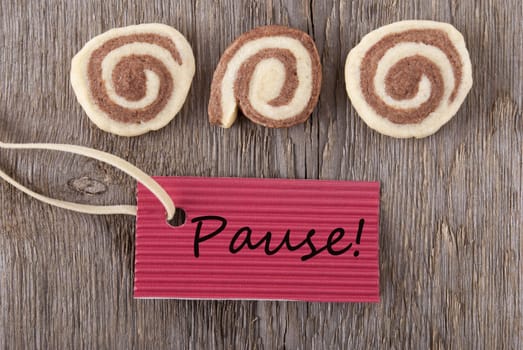 a red label with the german word Pause which means break on wooden background with cookies