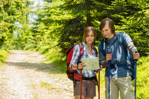 Young trekking couple standing and checking the map
