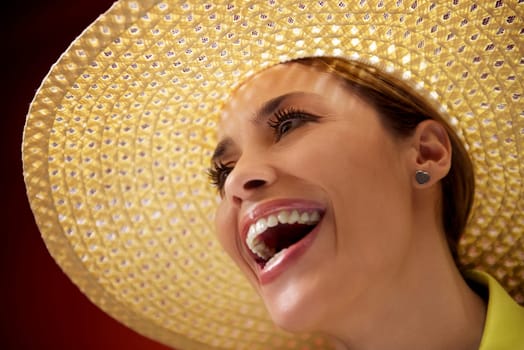 mid adult woman with straw hat smiling and looking up on red background