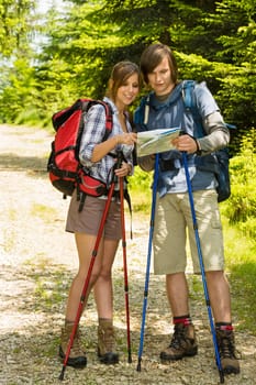 Young hiker couple standing and checking the map in nature