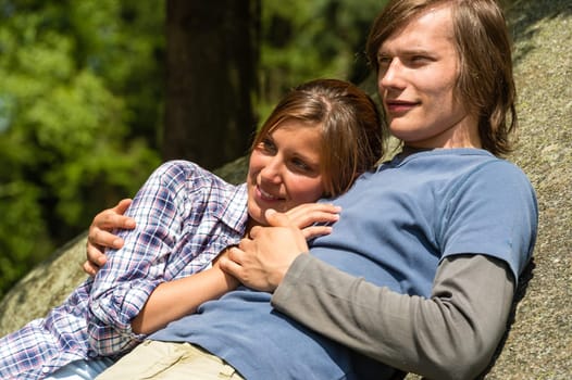 Young Caucasian couple enjoying sunshine lying on rock