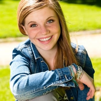 Joyful young girl enjoying sunshine outdoors wearing denim jacket