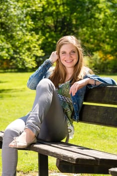 Adolescent girl enjoy sun on a bench outside in the park
