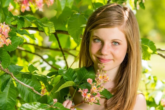 Girl in the sunshine smelling tree blossom in springtime