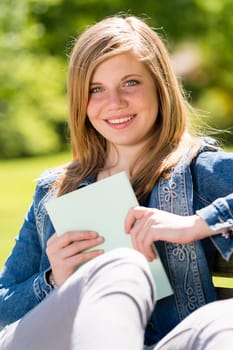 Teenage student sitting outside with notebook enjoying sunshine