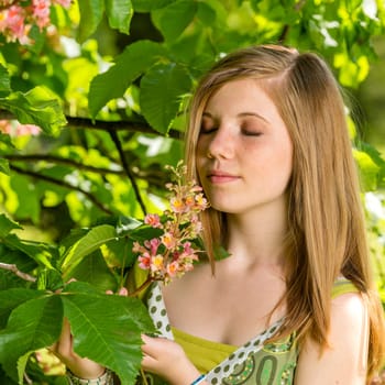 Young girl smelling blossom of the tree springtime