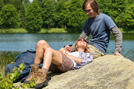 Cheerful trekking couple resting at lakeside