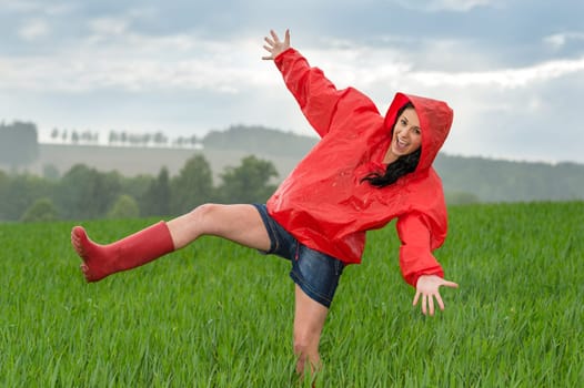 Playful teenage girl dancing in the rain on a field