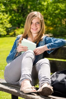 Young female student studying in the park sitting on bench