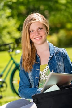 Student girl studying outside in the sunshine using tablet