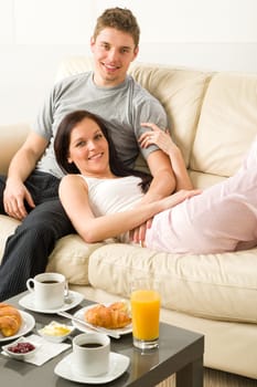 Lovely couple lying on couch in pajamas looking at camera