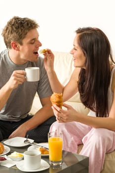 Carefree couple eating breakfast in pajamas at home