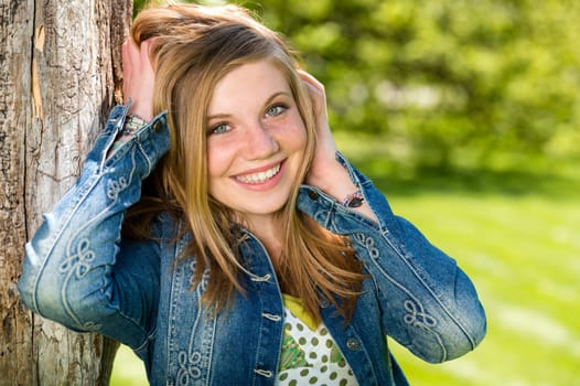 Portrait of overjoyed girl outside leaning to tree