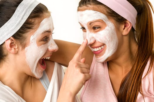 Playful teen wearing mask touches her friend's nose