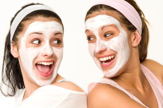Cheerful girls having facial mask and laughing at each other
