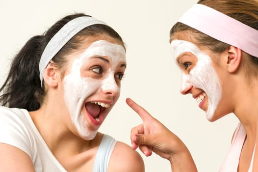 Joyful girls wearing white mask and laughing at each other