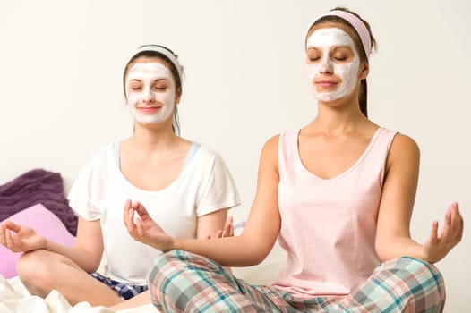 Meditating women sitting cross-legged  wearing white facial mask