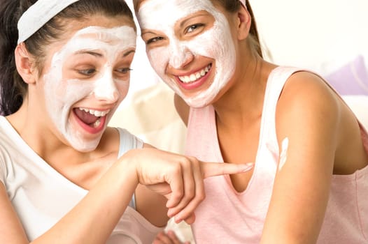 Laughing caucasian girls wearing peeling mask having fun