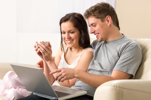 Cheerful couple using laptop together in living room