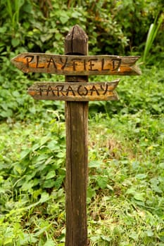 A unique and funny wooden sign pointing to two places "faraway"" and ""playfield"""