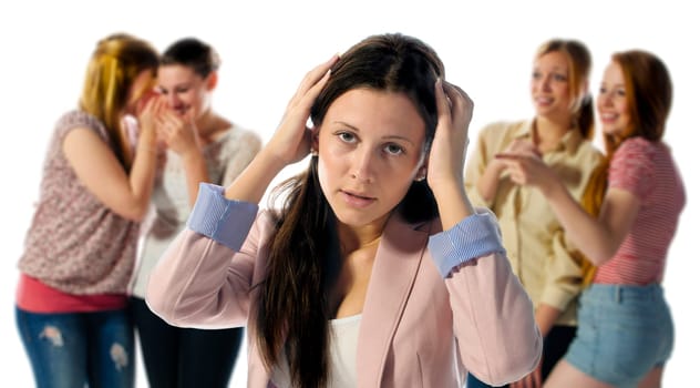 A dark haired girl is desperate and holds his hands to his head in the background are out of focus four girls who laugh at them.