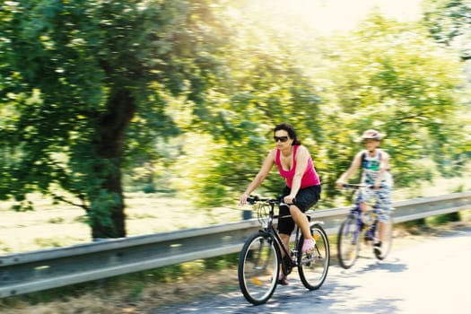 Mother with sons riding bicycle on trip in sunny day with motion blur