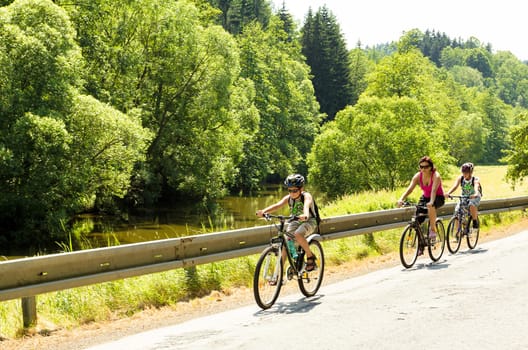 Mother with two sons riding bicycle on trip in sunny day