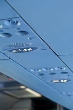 vertical color portrait captured in a passenger airline somewhere in europe shot passenger cabin ceiling and advisory lights for fasten seat belts and switch off electronic equipment and devices such as mobile phones