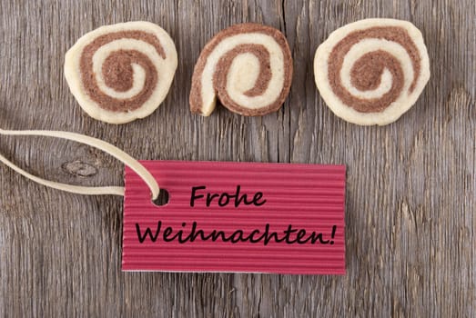 some cookies and a maker tag with the german words Frohe Weihachten, which means merry christmas as background
