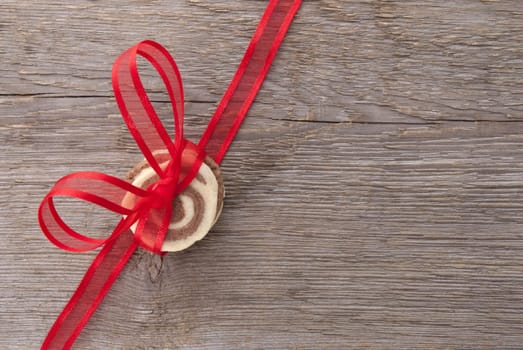 a red ribbon bow with cookies on a wooden background with copy space
