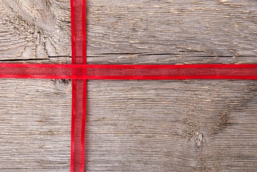 red ribbon on wood in shape of a cross with copy space as background