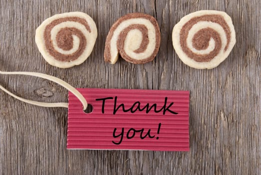 a red label with thank you on it with cookies on a wooden background