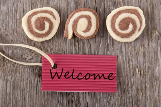 a red label with welcome on it and some cookies on a wooden background