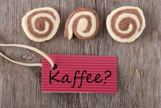 the german word Kaffee which means coffee on a red label with some cookies on wooden background