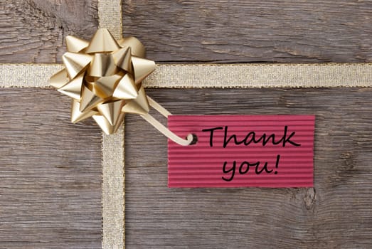 thank you on a red label on a golden gift bow as present background