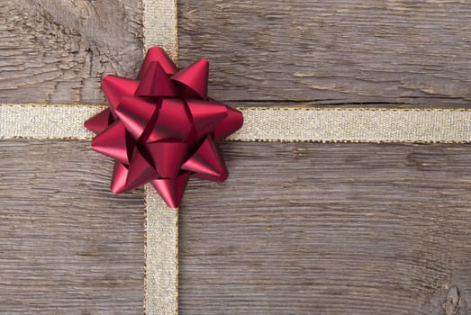 a red bow on a golden ribbon on wood as backgroun