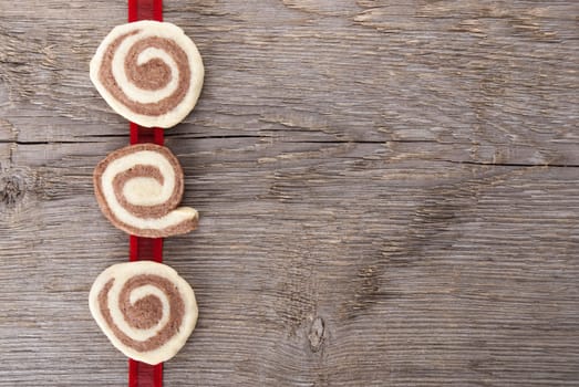 three cookies on a red ribbon on wooden background with copy space