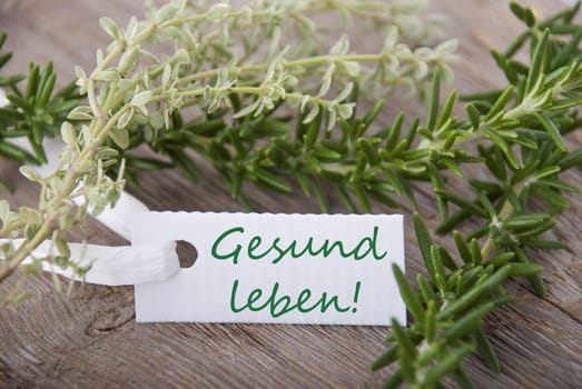 a tag with the german words Gesund leben which means live healthy with herbs in the background