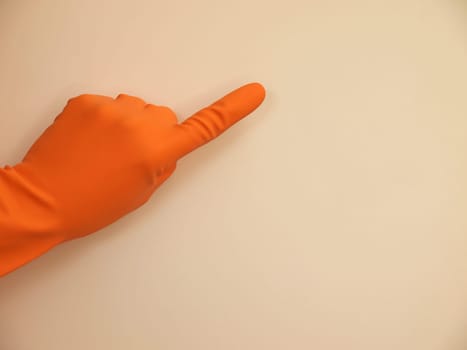 Hand with a rubber glove pointing on something, background with space for text or image