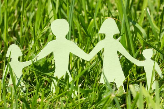 Paper family on  green grass in a bright day