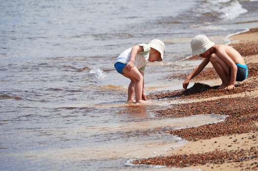 Two little boys playing on the sand beach
