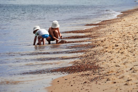 Two little boys playing on the sand beach